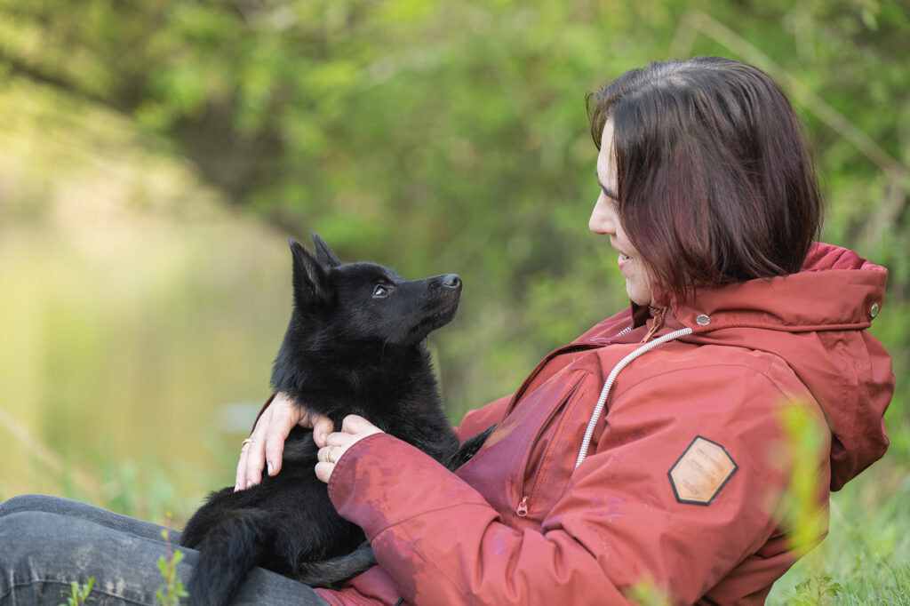 Frau und Hund kuscheln am Flussufer