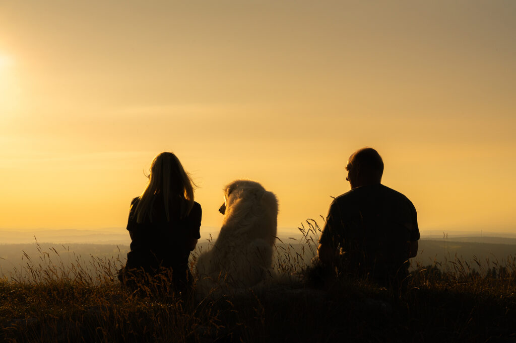 Mann, Frau und Hund schauen in die Landschaft
