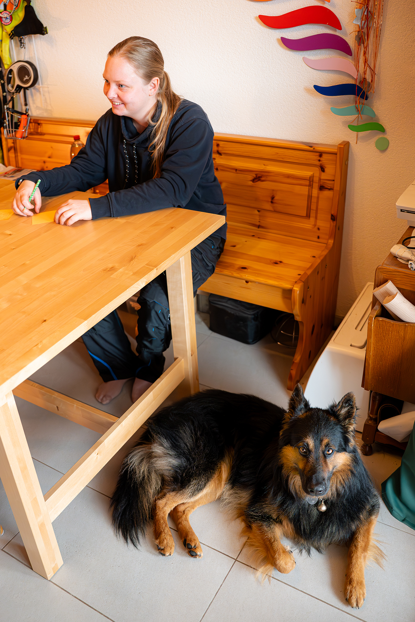 Eine Person sitzt mit Assistenzhund am Tisch