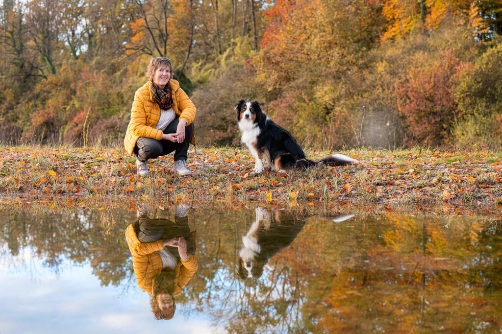 Frau und Hund spiegeln sich im Wasser