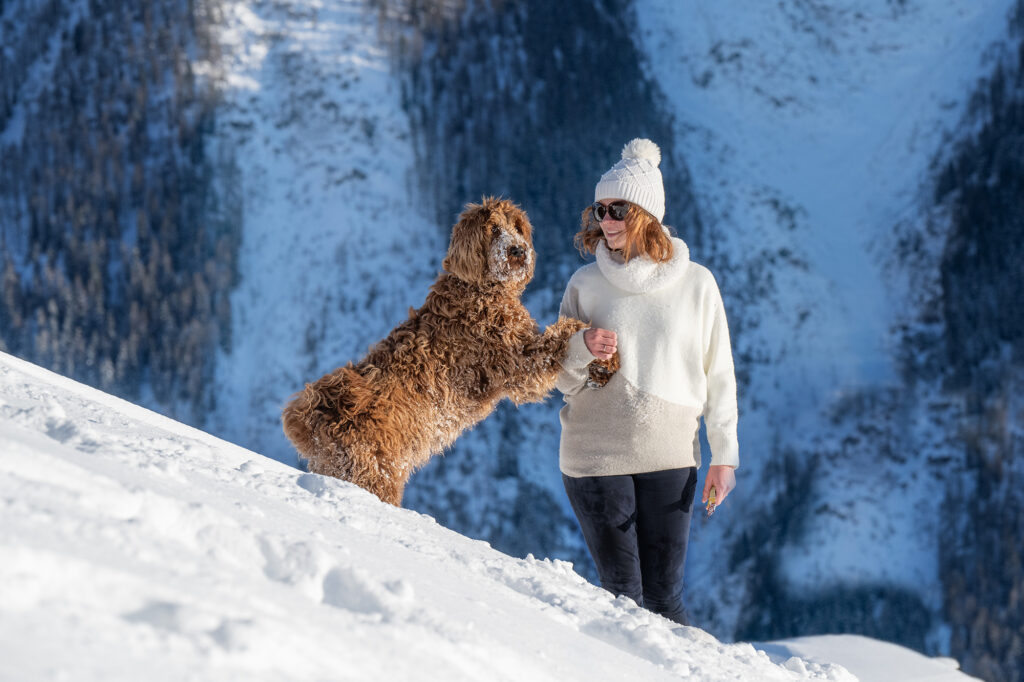 Frau spielt mit Hund im Schnee